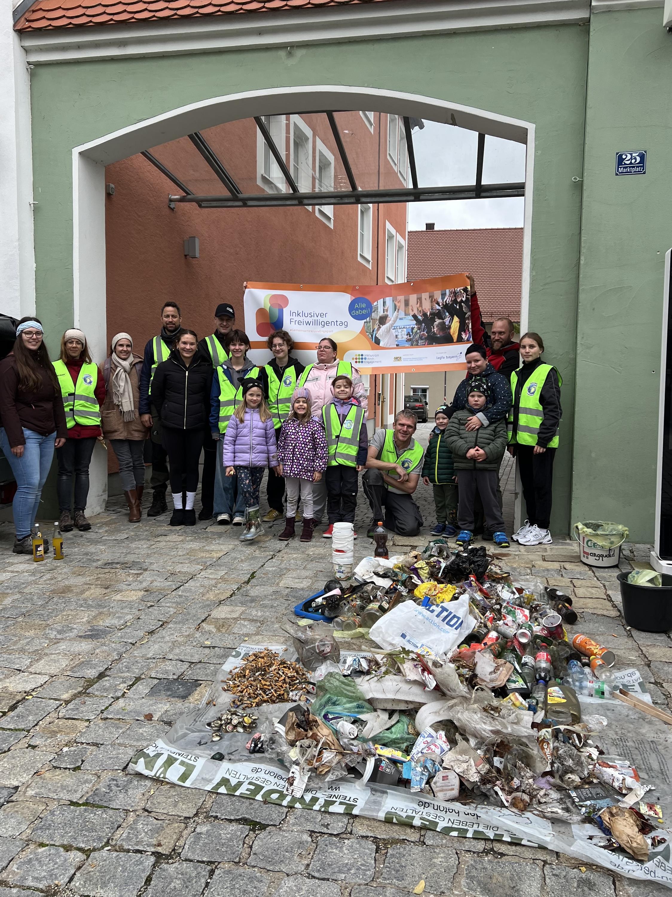 Teilnehmer des inklusiven Cleanups posieren hinter dem gefundenen Müll