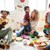 Vater und 2 Frauen sitzen am Boden wo vier Kinder miteinander spielen 