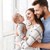 Vater und Mutter, die ihr Baby auf dem Arm hält, stehen vor Fenster  Vater und Mutter, die ihr Baby auf dem Arm hält, stehen vor Fenster