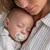 Frau hält schlafenden Babys mit Schnuller im Mund auf dem Arm Frau hält schlafenden Babys mit Schnuller im Mund auf dem Arm