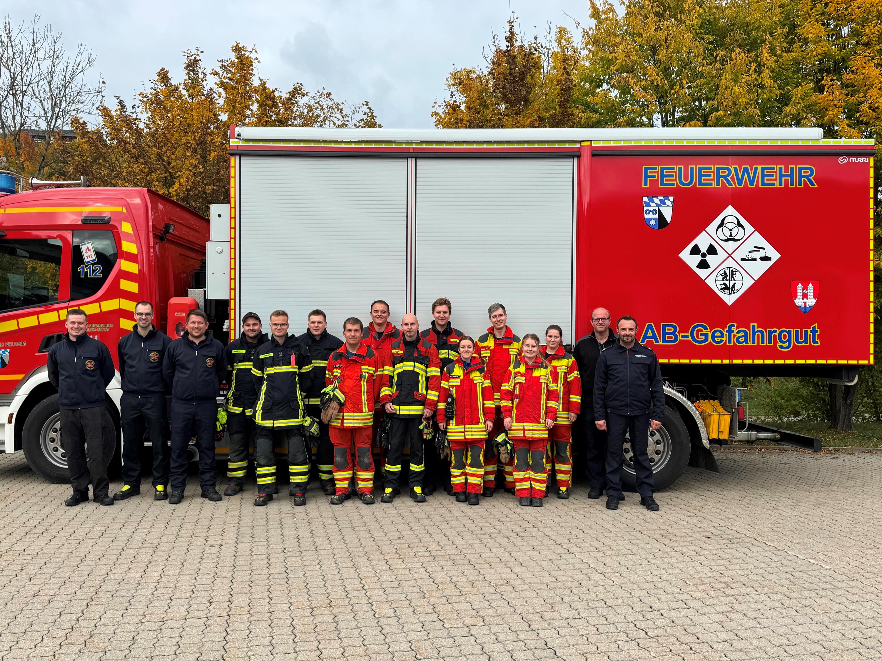Lehrgang „Träger von leichten Chemikalienschutzanzügen“ Insgesamt 16 Feuerwehrmänner und -frauen stehen vor dem Feuerwehrauto
