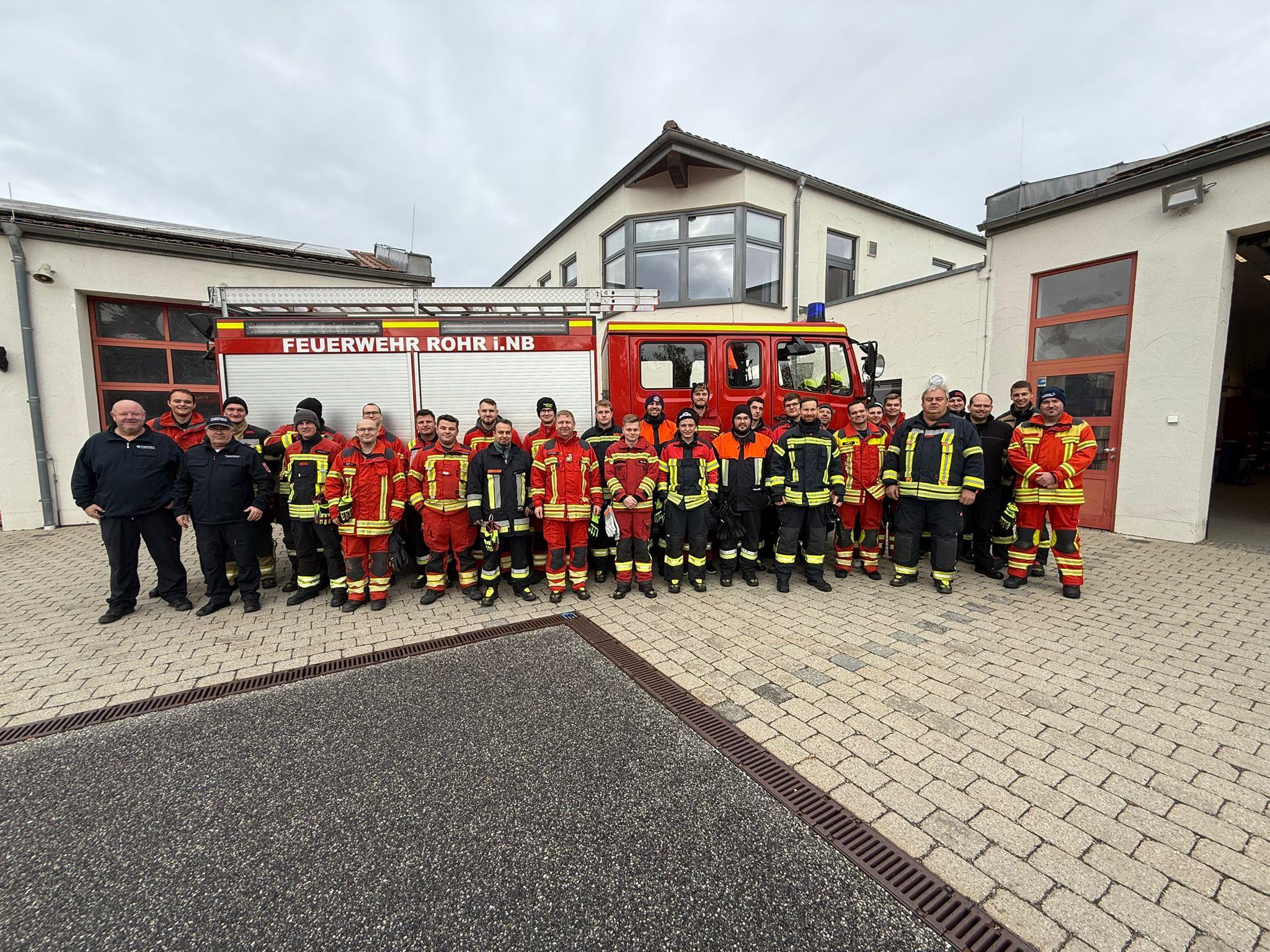 32 Feuerwehrmänner stehen vor einem Feuerwehrauto