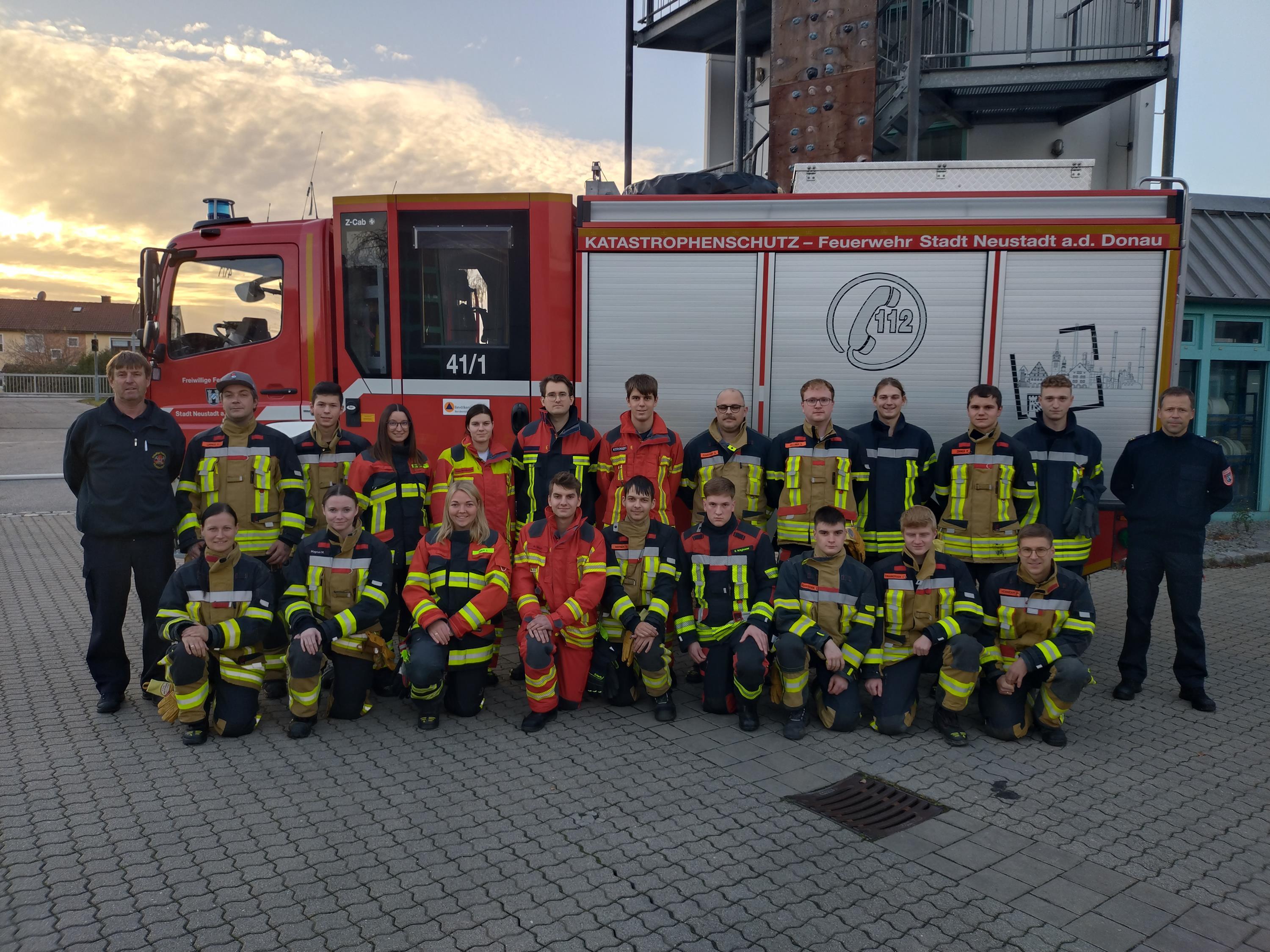 22 Feuerwehrleute stehen neben vor einem Feuerwehrauto