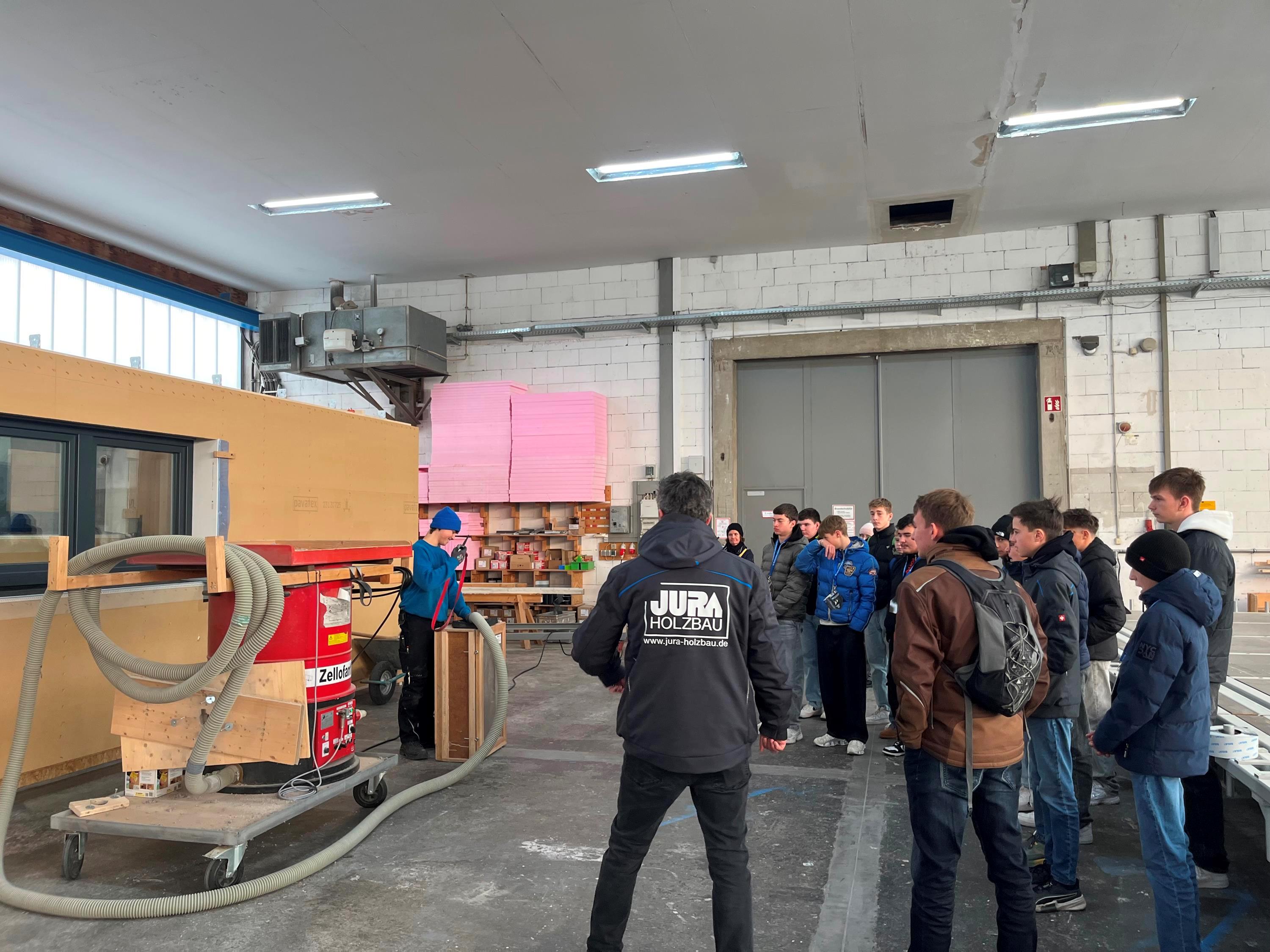 Ein Zimmerer-Azubi zeigt Schülern, wie er mit Holz arbeitet.