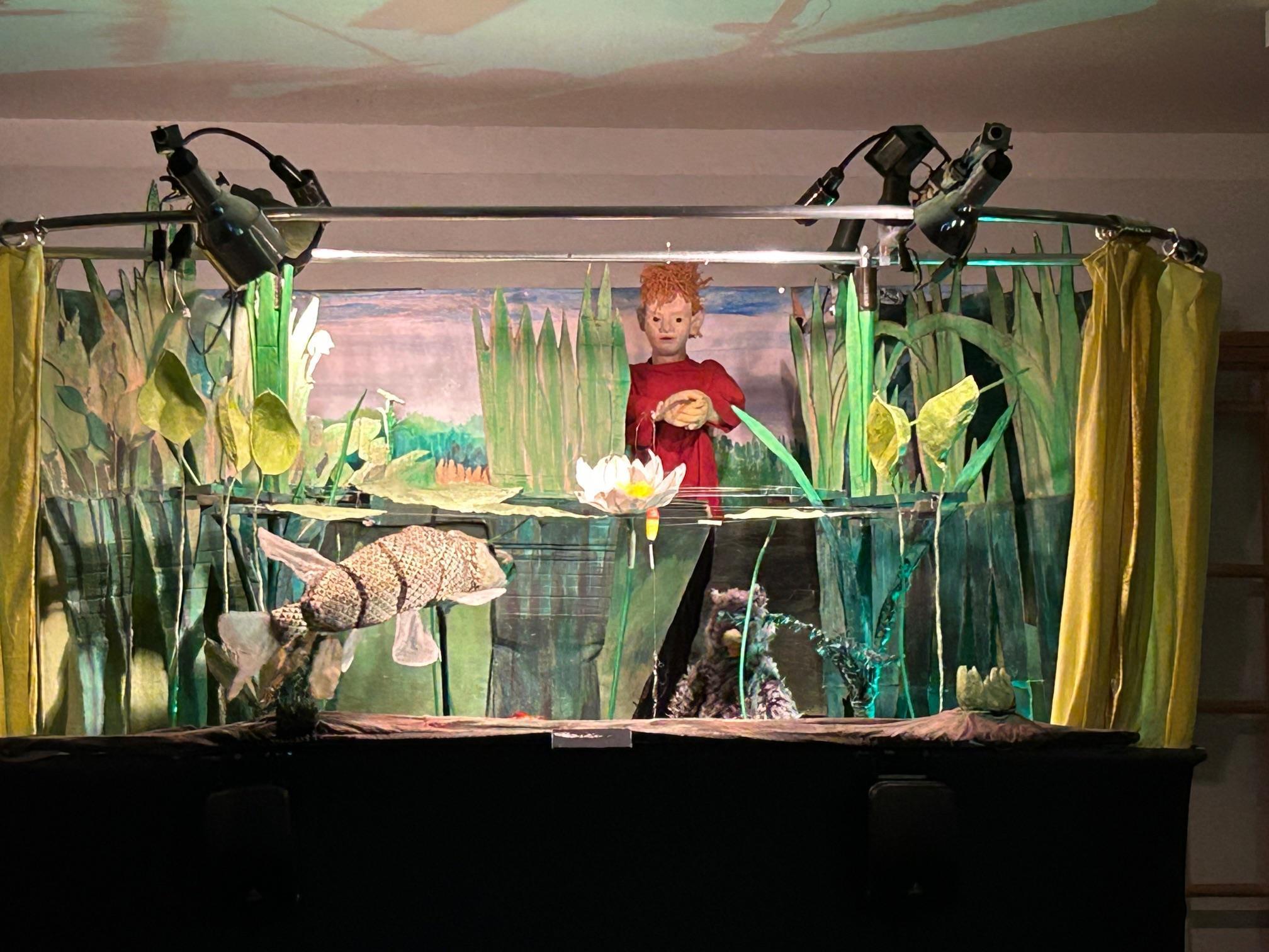 Im Puppentheater werden ein Mensch und ein Fisch im Teich dargestellt