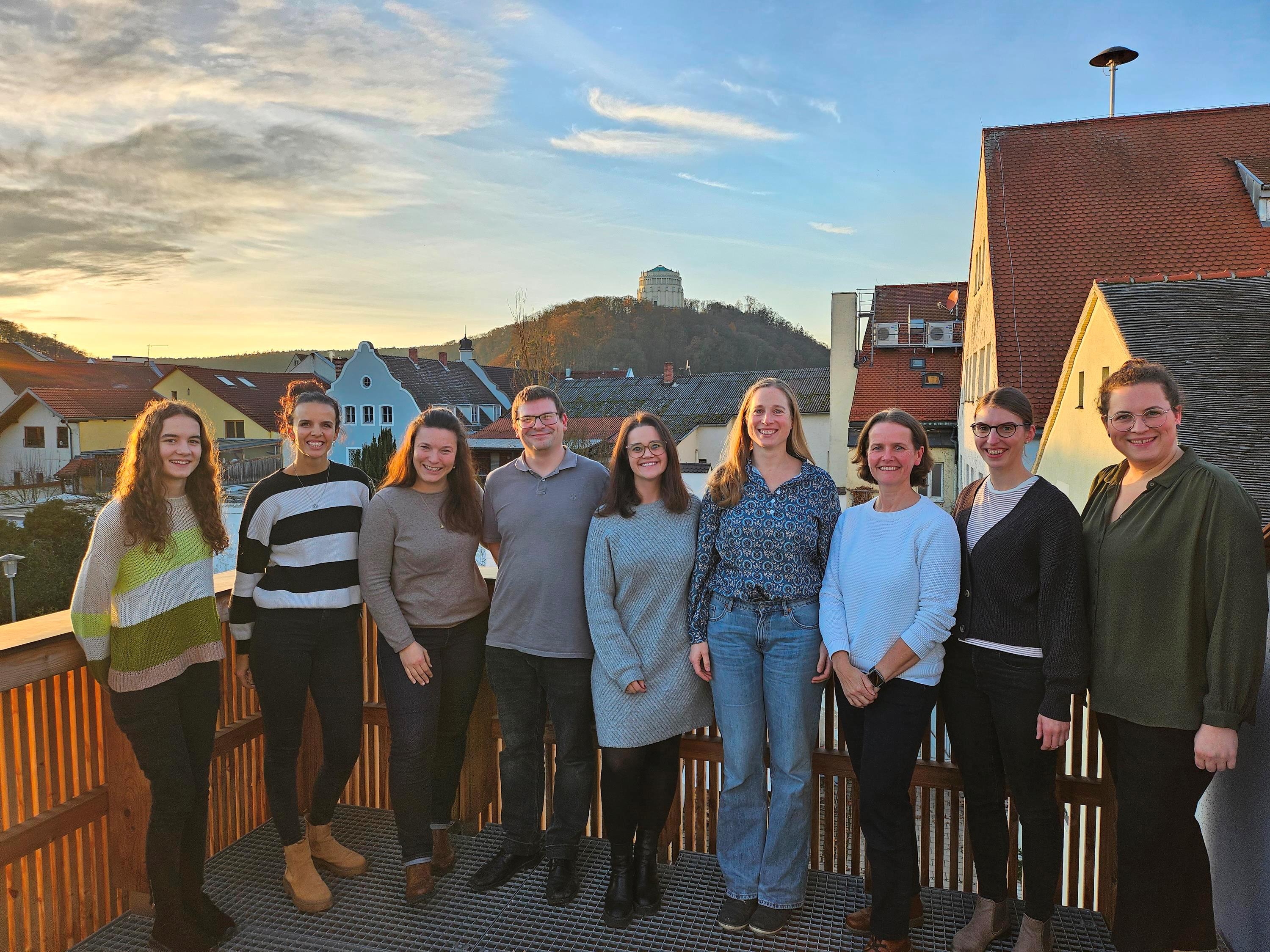 Neun Personen auf einem Balkon mit der Befreiungshalle im Hintergrund