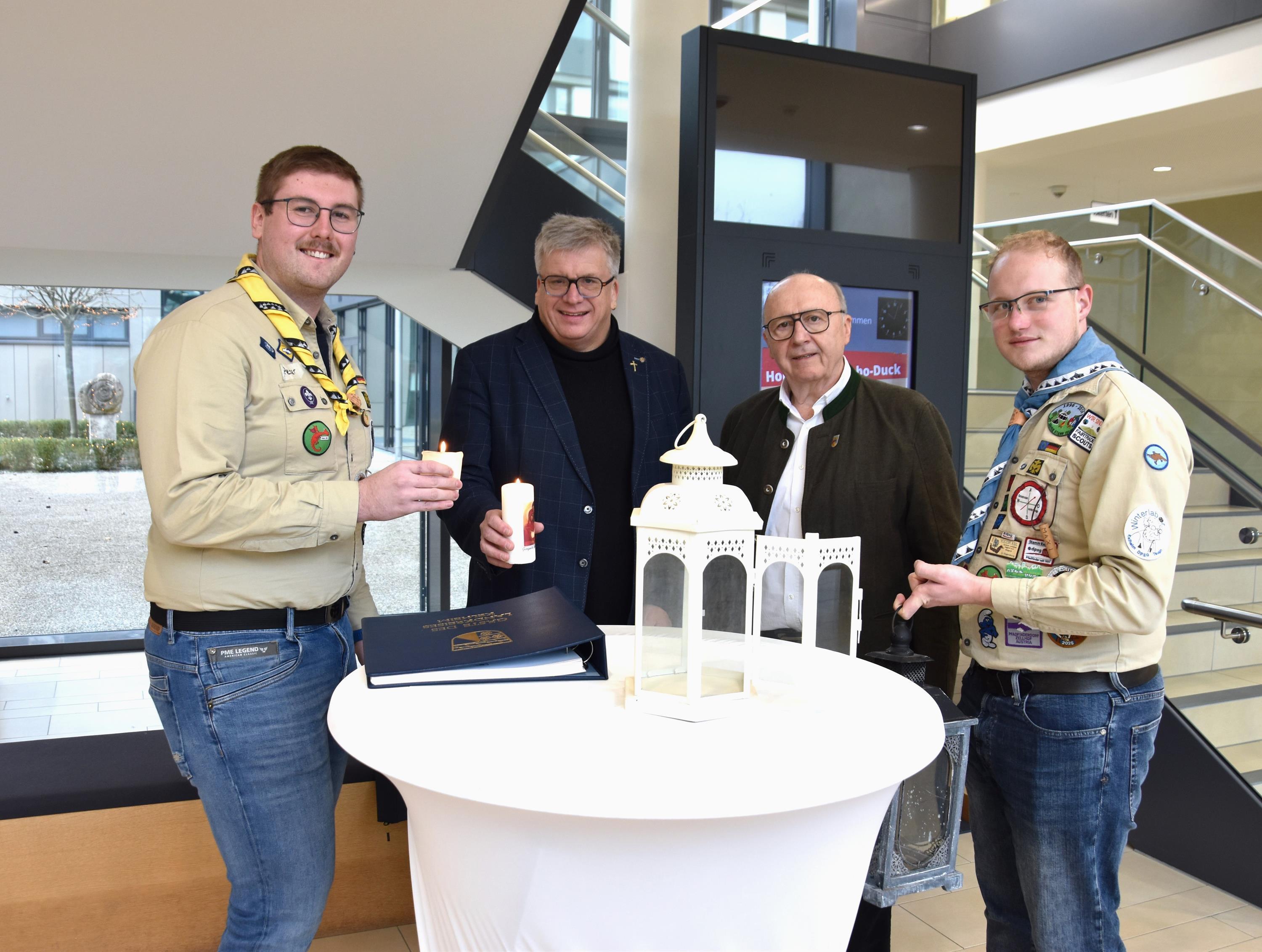 Zwei Pfadfinder, Pfarrer und Landrat halten zwei brennende Kerzen