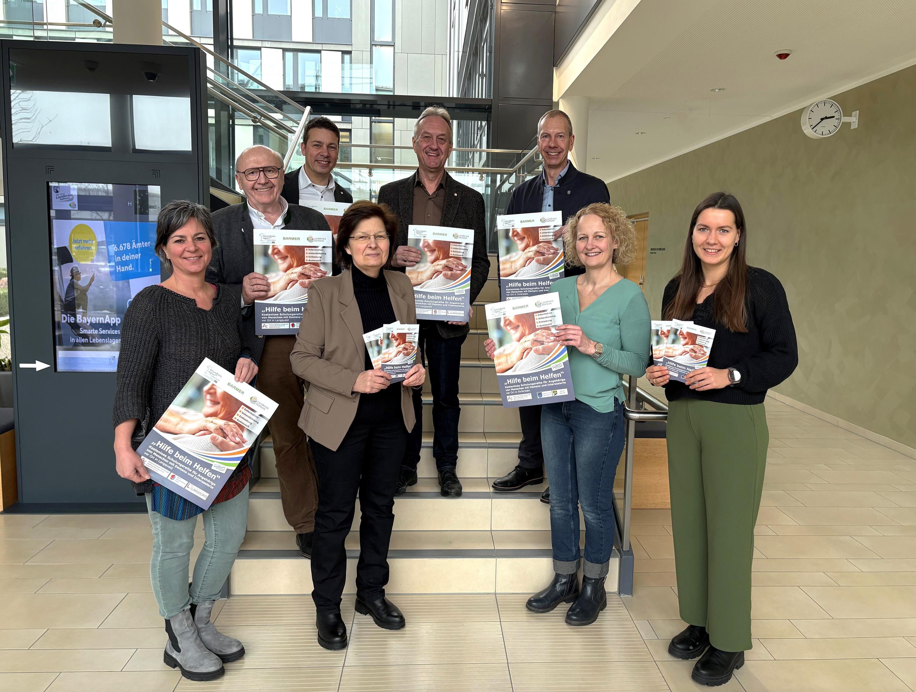 Vier Männer und vier Frauen präsentieren das Plakat zur Schulungsreihe