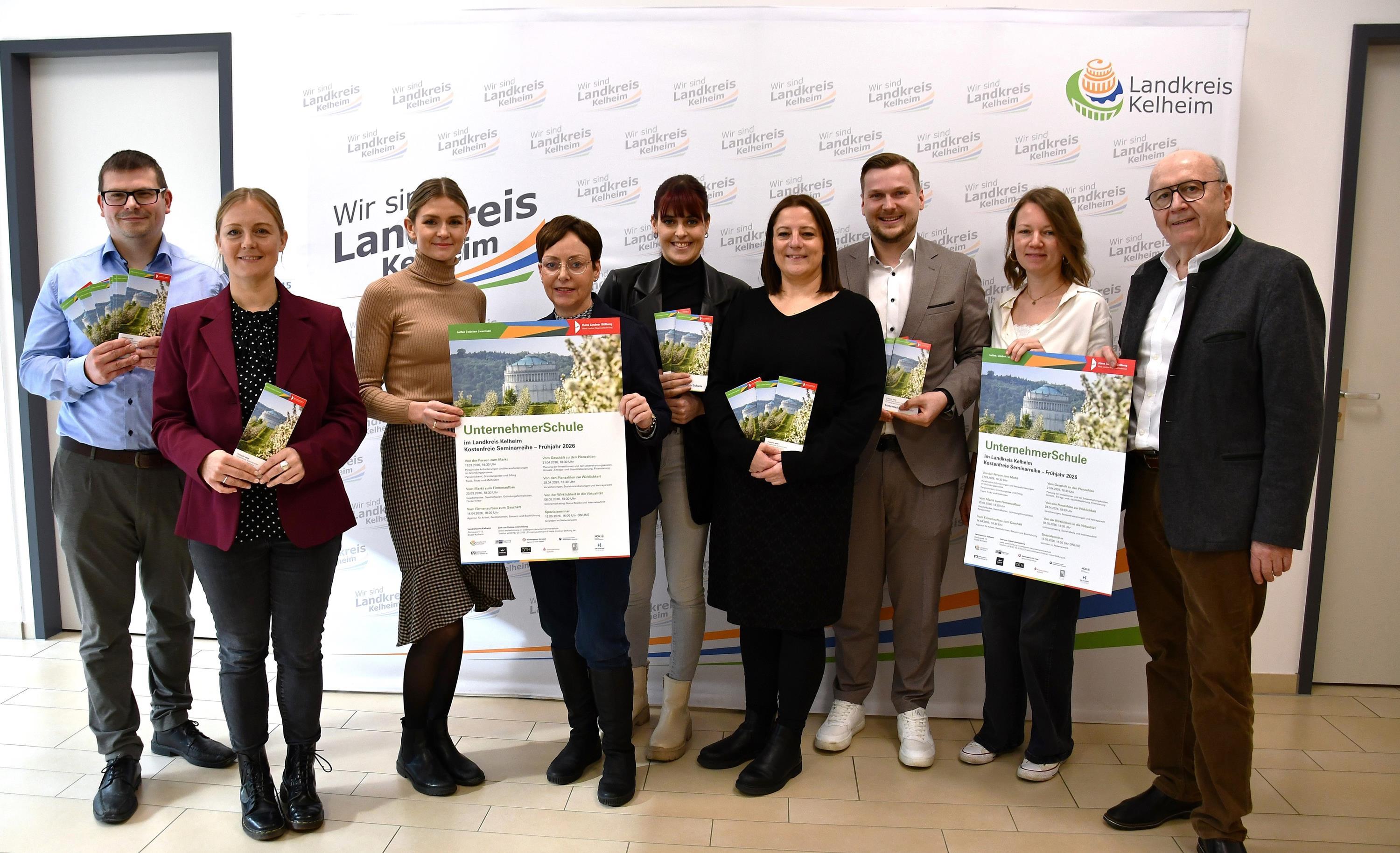 Zwei Männer und sieben Frauen präsentieren Flyer der Unternehmerschule