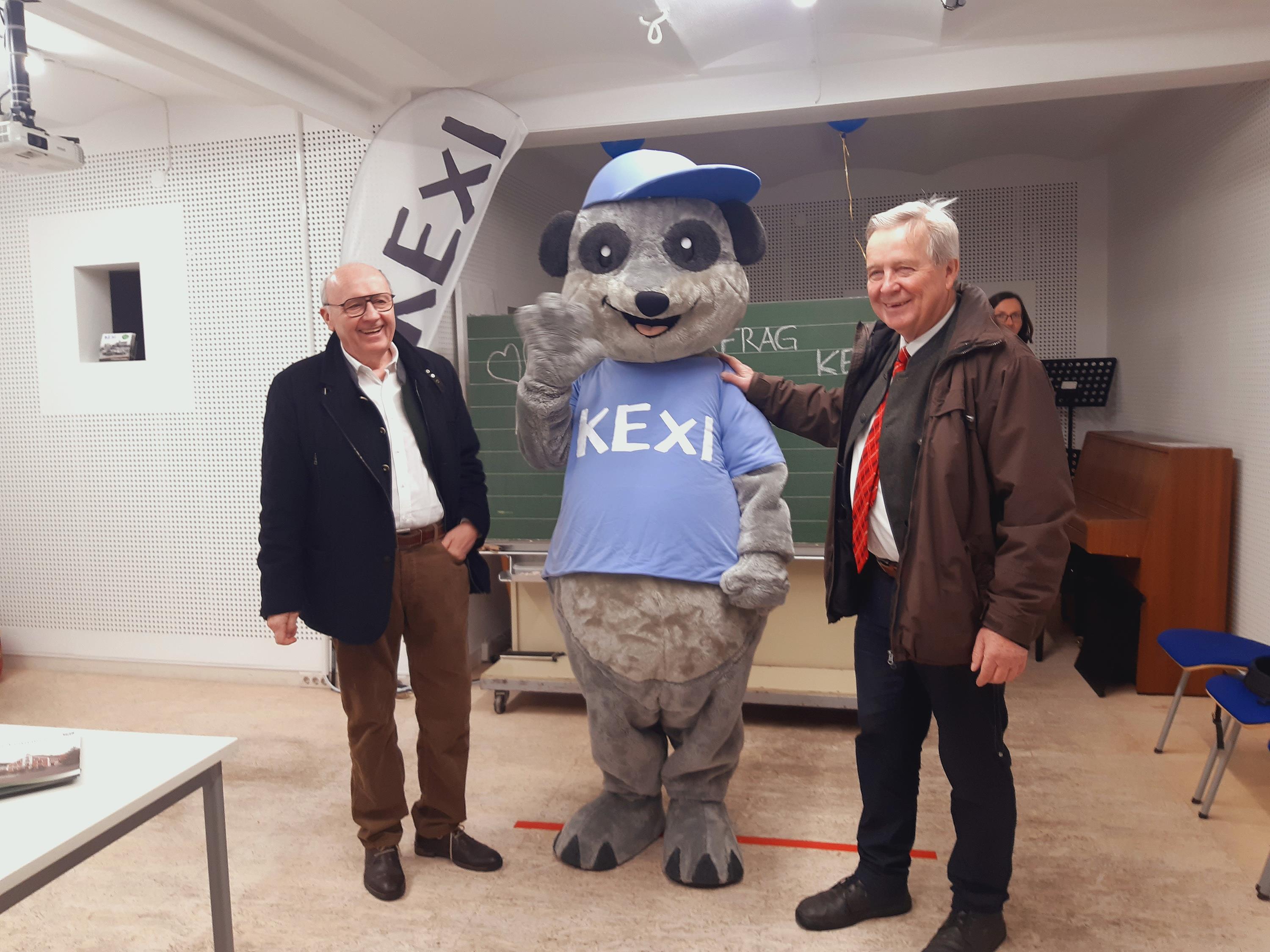 Landrat, Erdmännchen-Maskottchen und Bürgermeister vor Schultafel