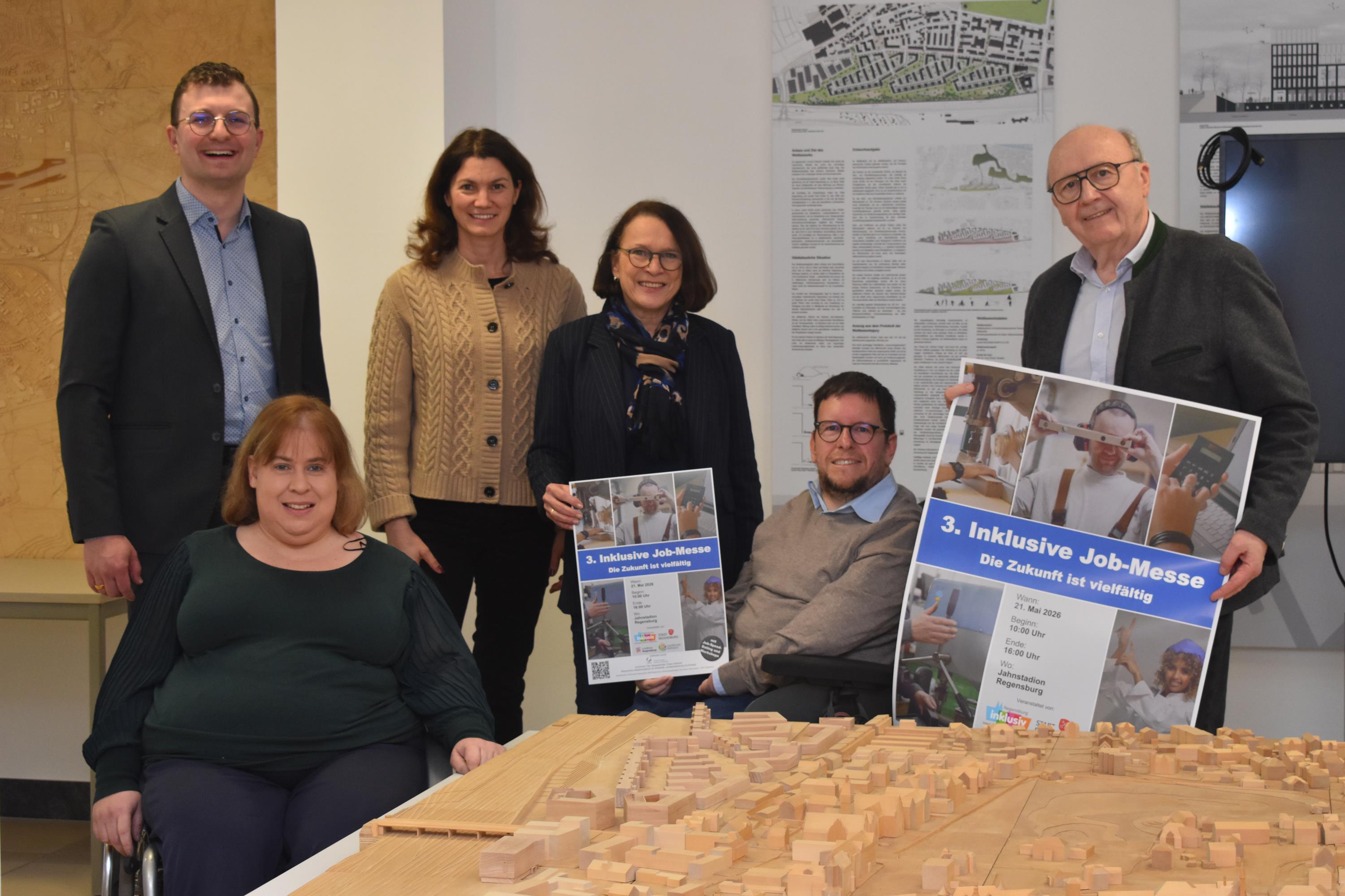 Zwei Männer, zwei Frauen und zwei Rollstuhlfahrer präsentieren Flyer.