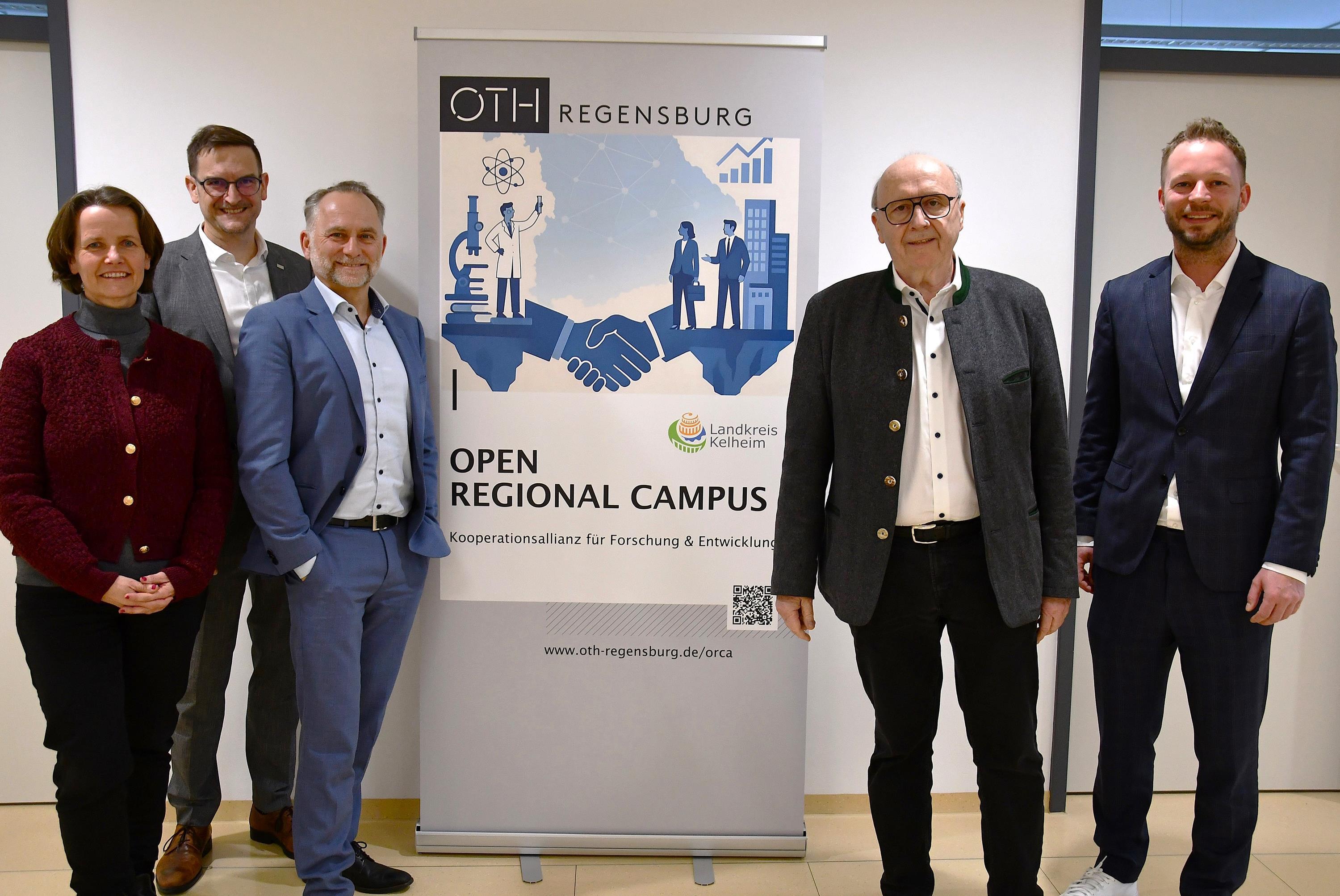 Vier Männer und eine Frau flankieren ein Rollup-Banner.