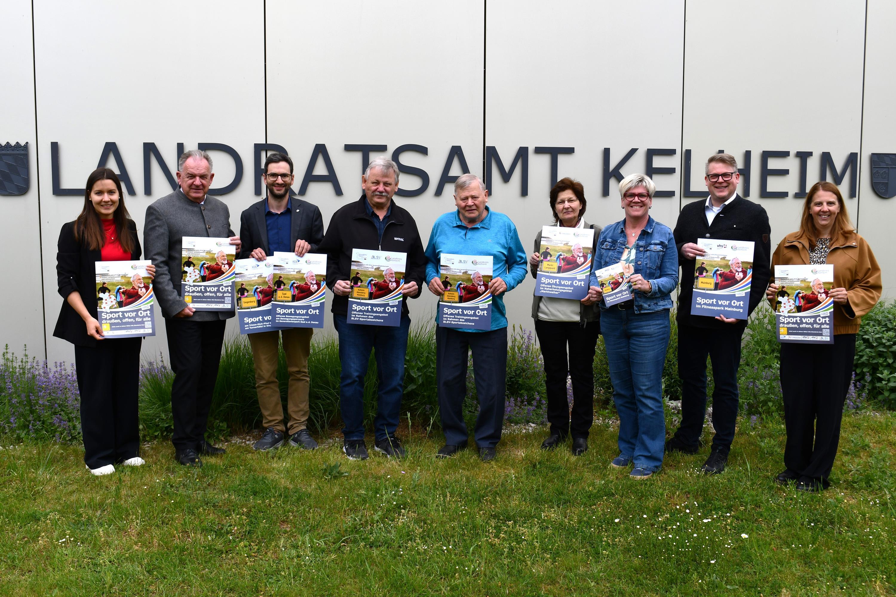 Neun Personen vor dem Landratsamt mit dem Plakat Sport vor Ort