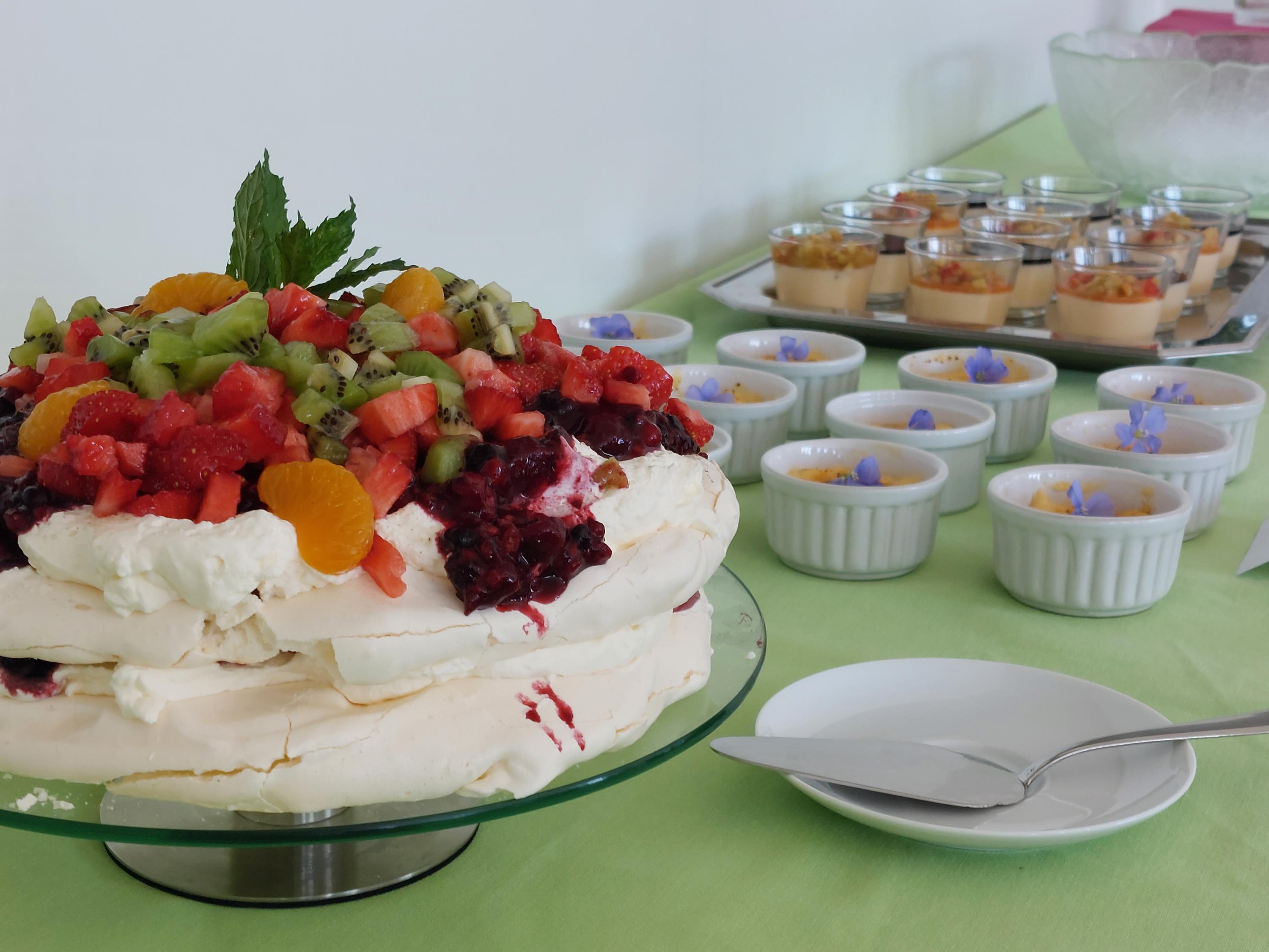 Nachspeisenbuffet mit Obst-Sahnetorte links und Schälchen und Gläsern