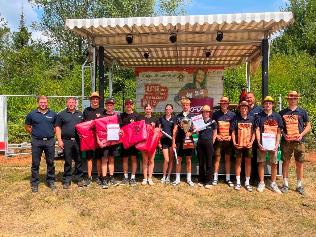 3 Erwachsene und 11 Jugendliche mit Geschenken und Pokal im Arm