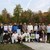 18 Männer und 2 Frauen mit Cricketschlägern und Plakaten auf Wiese